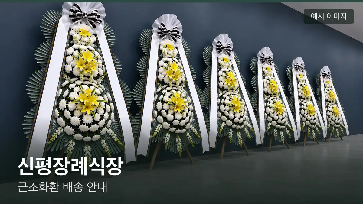 신평장례식장 근조화환 예시 이미지 — 흰 국화 3단 근조화환이 벽을 따라 나란히 놓인 모습
