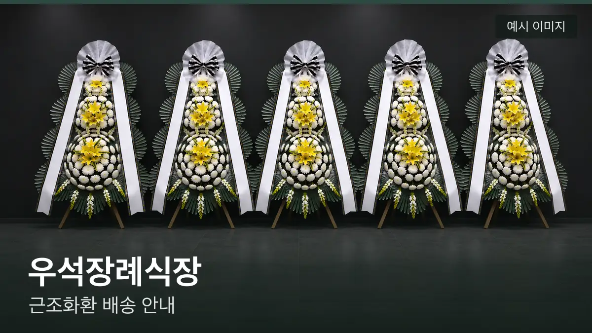 우석장례식장 근조화환 예시 이미지 — 흰 국화 3단 근조화환이 벽을 따라 나란히 놓인 모습