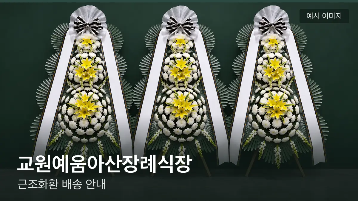 교원예움아산장례식장 근조화환 예시 이미지 — 흰 국화 3단 근조화환이 벽을 따라 나란히 놓인 모습