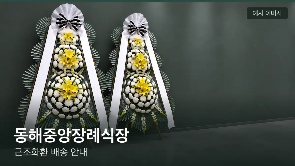 동해중앙장례식장 근조화환 예시 이미지 — 흰 국화 3단 근조화환이 벽을 따라 나란히 놓인 모습
