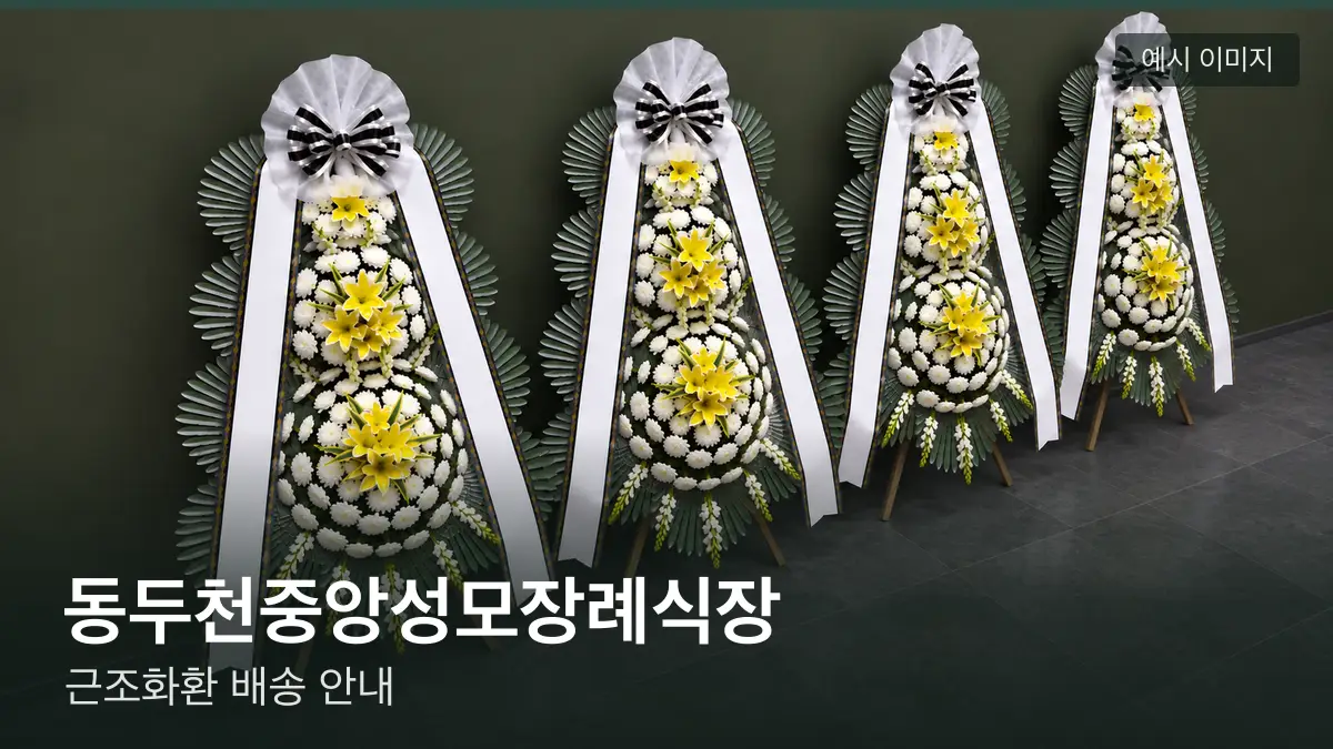 동두천중앙성모장례식장 근조화환 예시 이미지 — 흰 국화 3단 근조화환이 벽을 따라 나란히 놓인 모습