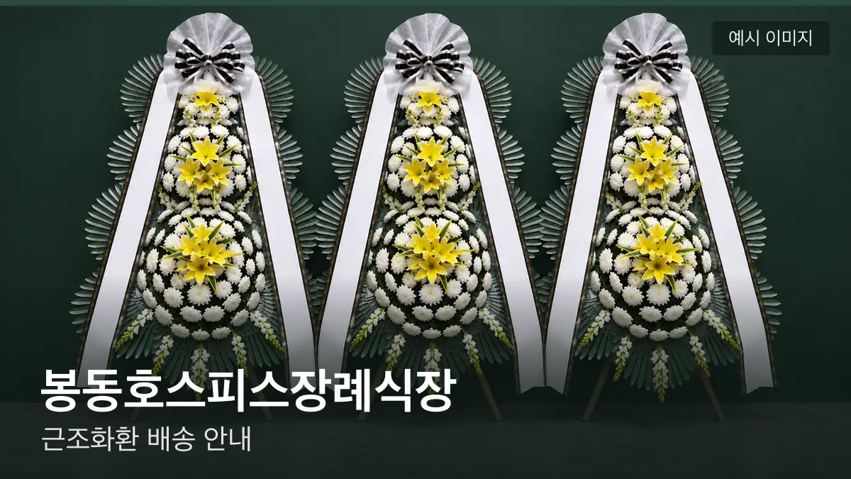 봉동호스피스장례식장 근조화환 예시 이미지 — 흰 국화 3단 근조화환이 벽을 따라 나란히 놓인 모습