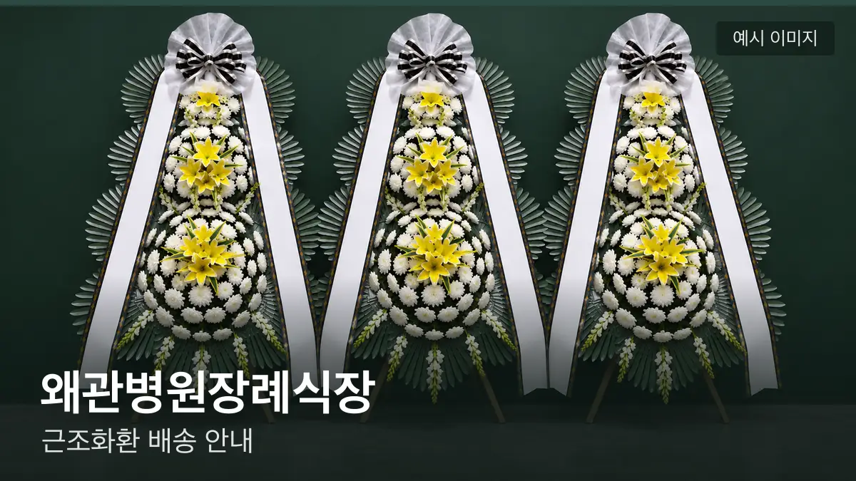 왜관병원장례식장 근조화환 예시 이미지 — 흰 국화 3단 근조화환이 벽을 따라 나란히 놓인 모습