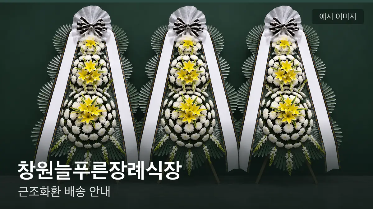 창원늘푸른장례식장 근조화환 예시 이미지 — 흰 국화 3단 근조화환이 벽을 따라 나란히 놓인 모습