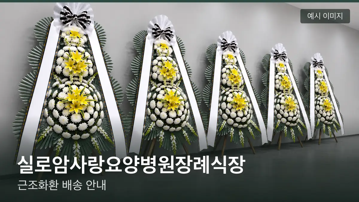 실로암사랑요양병원장례식장 근조화환 예시 이미지 — 흰 국화 3단 근조화환이 벽을 따라 나란히 놓인 모습