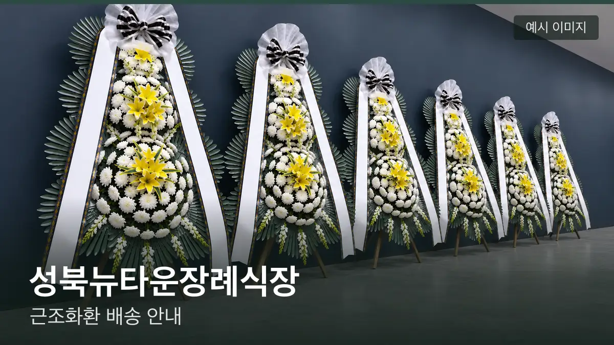 성북뉴타운장례식장 근조화환 예시 이미지 — 흰 국화 3단 근조화환이 벽을 따라 나란히 놓인 모습