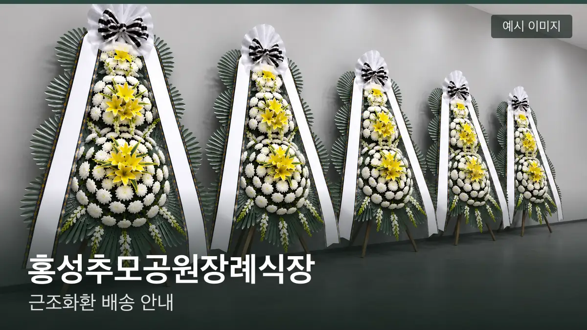 홍성추모공원장례식장 근조화환 예시 이미지 — 흰 국화 3단 근조화환이 벽을 따라 나란히 놓인 모습
